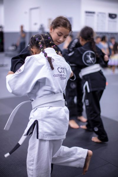 Kids practicing Brazilian Jiu-Jitsu in a dojo.