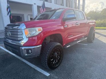 Red Toyota Tundra pickup truck parked outdoors under sunlight.