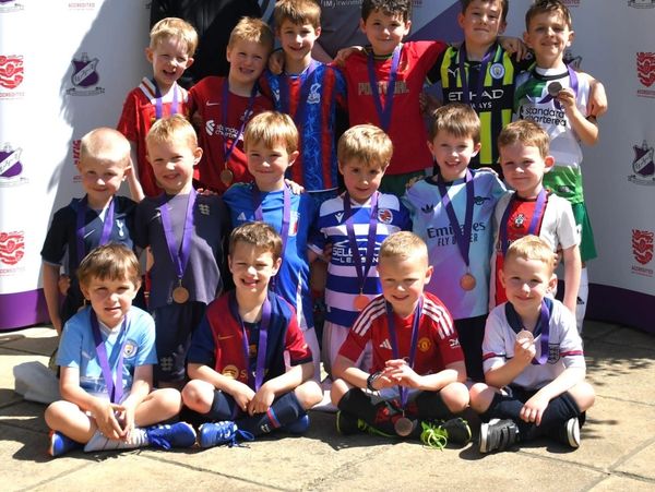 A group of young boys wearing football jerseys and medals.