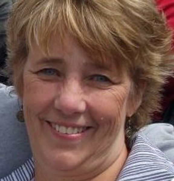 Smiling woman with short blonde hair and blue eyes.