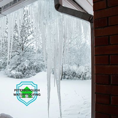 Large icicles hanging from a roof in a snowy winter scene.