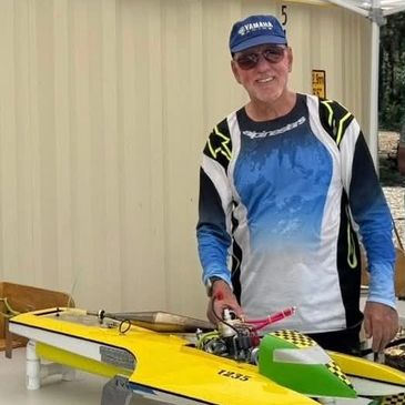 Man smiling with a yellow model boat.