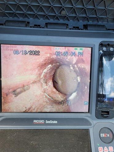 Close-up of a pipe inspection camera screen showing an internal pipe blockage.