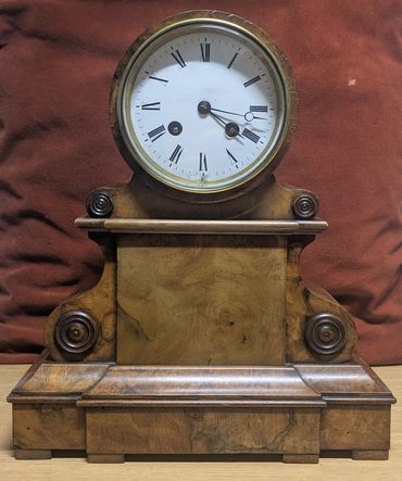 Antique wooden mantel clock with Roman numerals and ornate design.