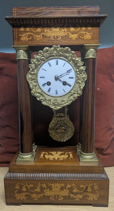 Antique wooden mantel clock with ornate gold detailing and Roman numerals.