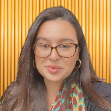 Woman with glasses and long hair smiling.