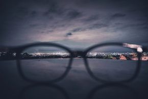 Photo looking through glasses lenses at city lights below.