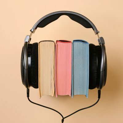 Decorative photo featuring 3 different colored books with headphones spread across them. 