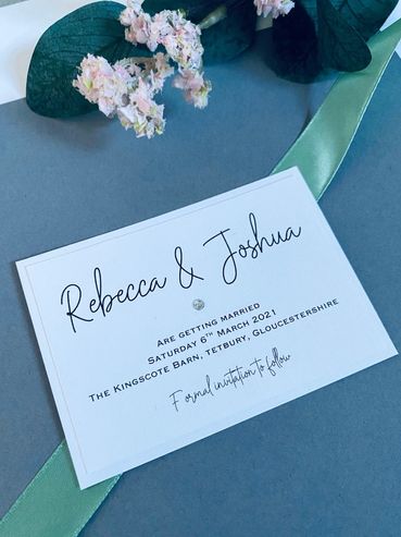 White, Save the Date Invitations with green ribbon and and diamond embellishment.