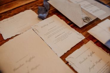 Wedding Invitation set with a vellum wrap, blue ribbons and a grey wax seal, lay on wooden table