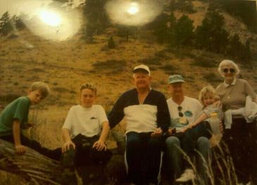 Family posing outdoors on a hillside.