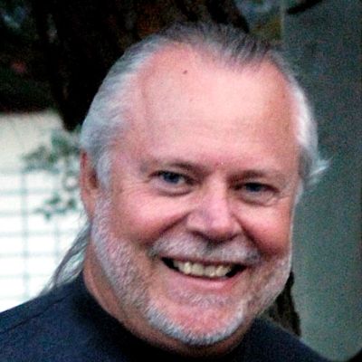 Smiling elderly man with gray hair and beard.