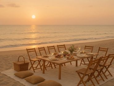 Elegant beachside dining setup at sunset with wooden chairs and table.