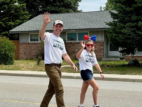 Man and girl waving while walking on the street.