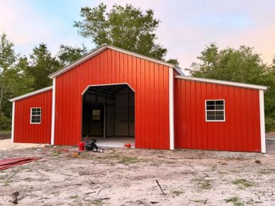 Red barn with white trim on a bare ground.