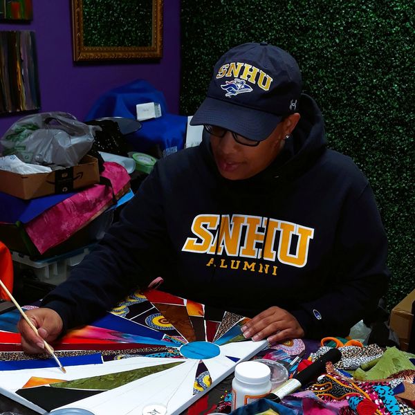 Artist sitting down at a table painting.