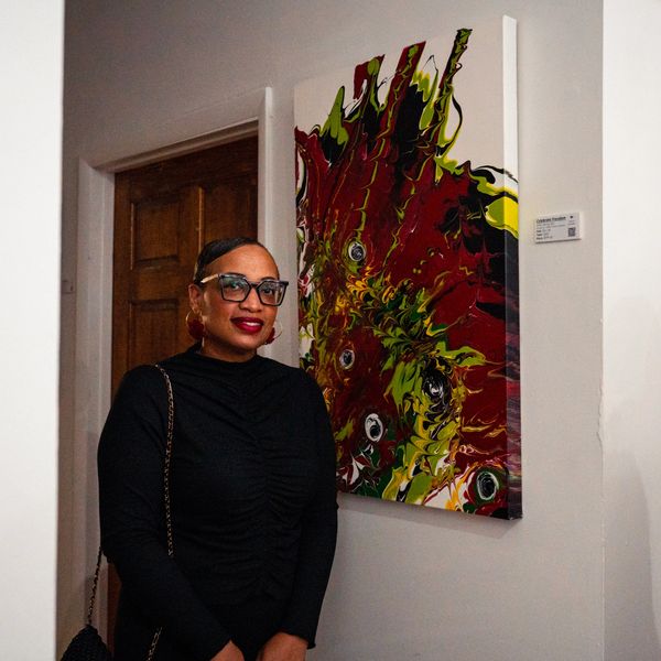 Artist smiling standing next to a painting.