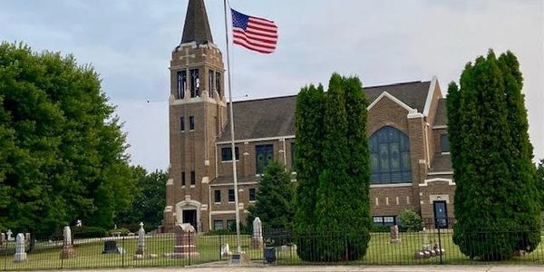 Church with American flag and surrounding cemetery.