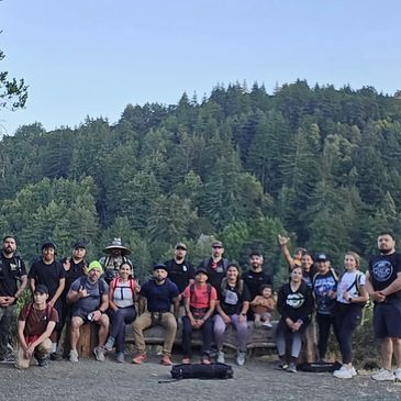 Group of hikers posing in front of a forested mountain landscape.