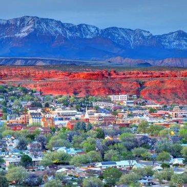 Cityscape with red cliffs and mountains in the background.