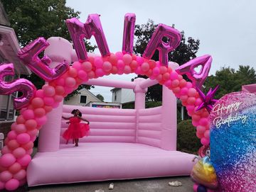 Pink bounce house with balloon arch in front, balloon nam arch