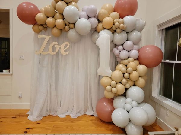 Custom balloon colors for a 1st birthday with sheer white drapes and laser cut wooden name sign