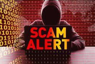 A suspicious hooded figure with the words scam alert highlighted in front of him.