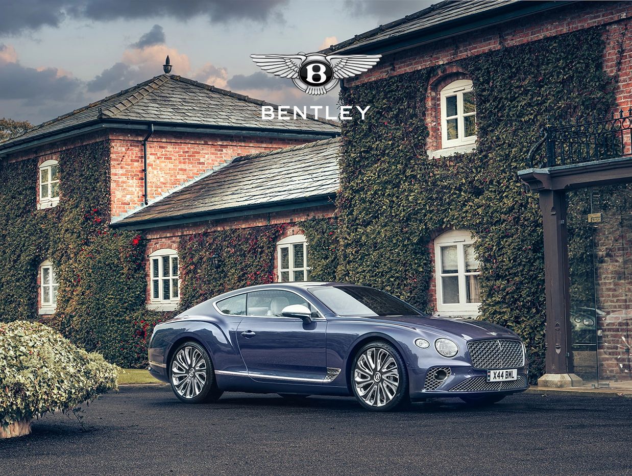 A Bentley car parked in front of a ivy-covered brick building.