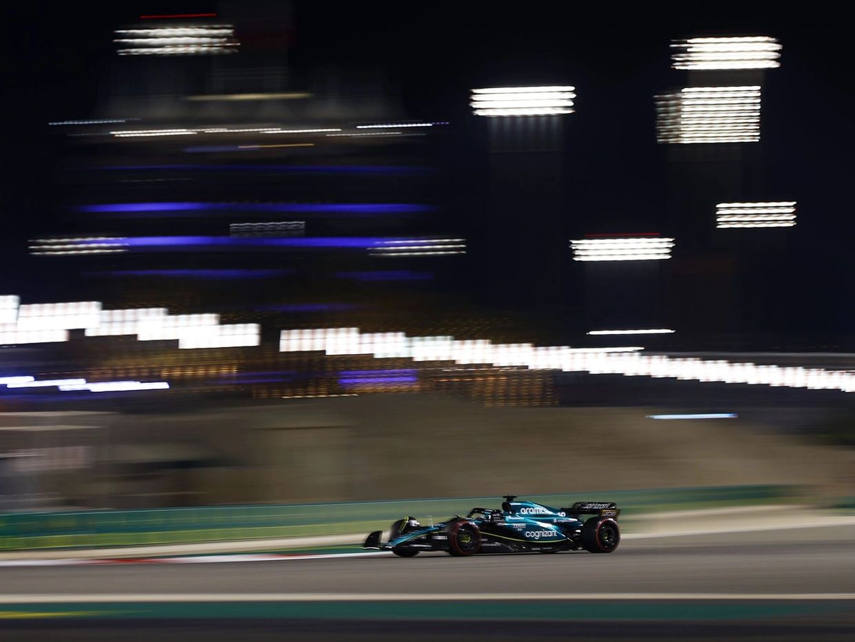 A Formula 1 car races at night with blurred lights in the background.