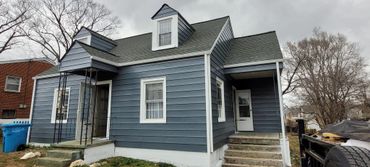 Blue-gray house with white trim and two stair entrances on a cloudy day.
