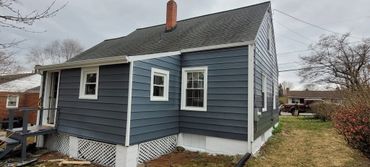 A blue house with white trim and a small porch under an overcast sky.