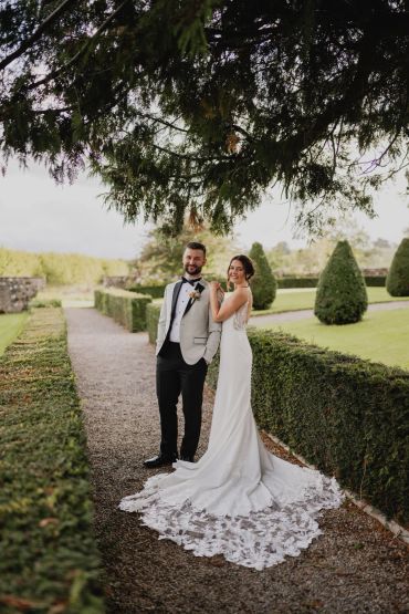 Bride and groom posing in a garden.