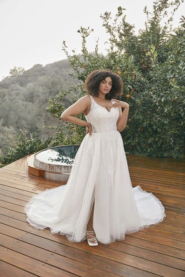 Woman in a white wedding dress standing on wooden deck.