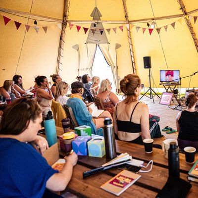 People attending an indoor talk or workshop in a decorated tent.