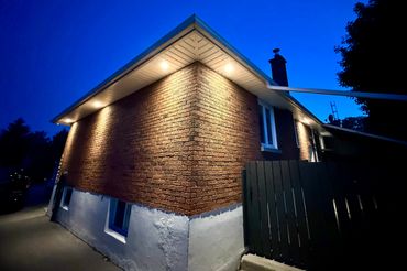 Evening view of a brick house corner with warm outdoor lights.