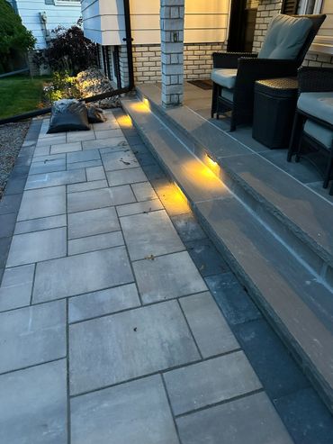 Outdoor stone steps with warm yellow lights and cushioned wicker chairs on the porch.