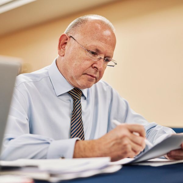 Focused businessman reviewing documents at his desk with a laptop.