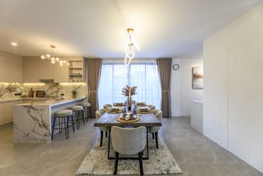 Modern dining area with a wooden table and marble kitchen island.