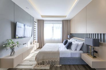 Bright modern bedroom with a large bed and wall-mounted TV.