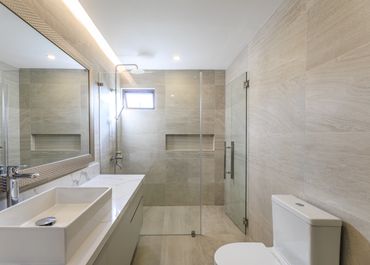 Modern bathroom with beige tiles, glass shower, and white fixtures.