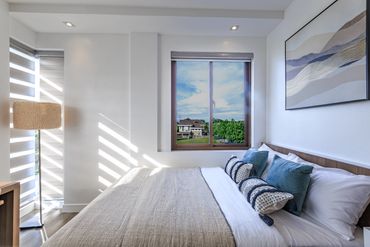 Bright, modern bedroom with large window and cozy bed.