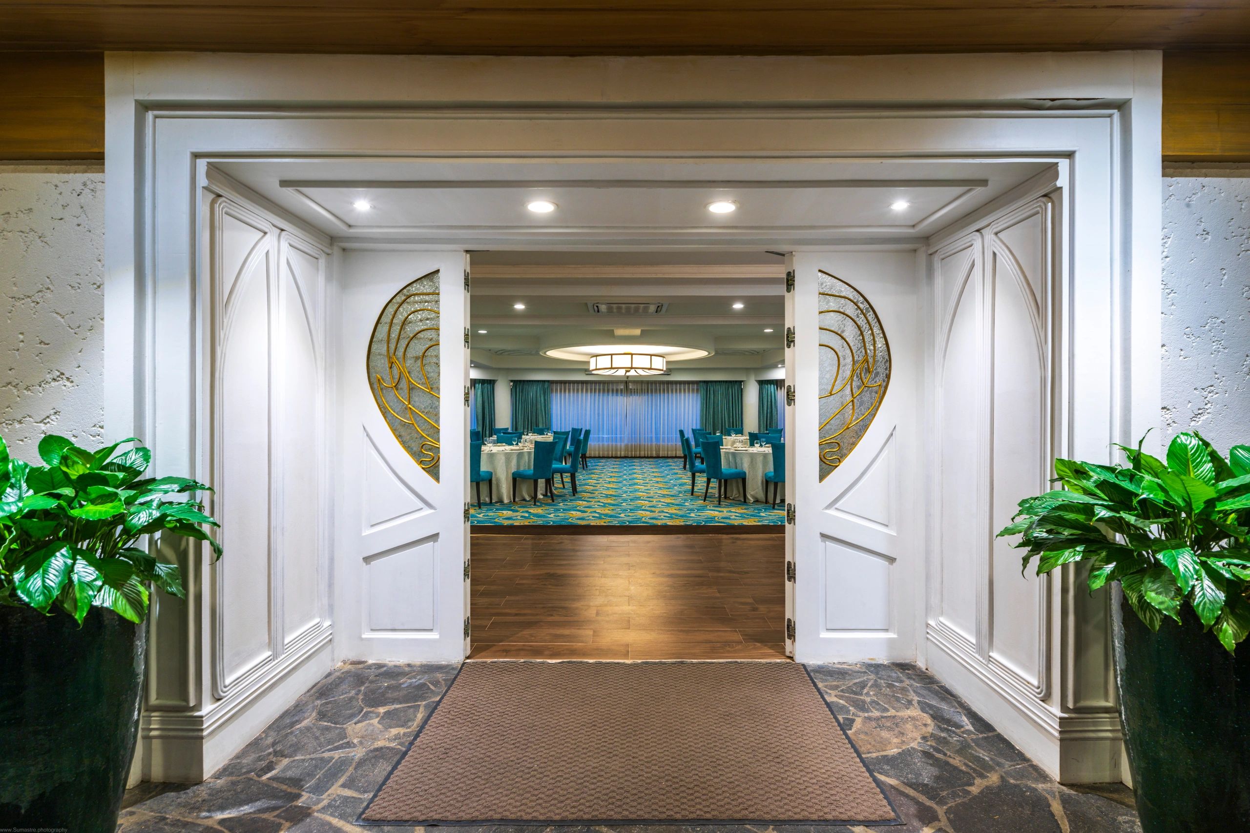 Open white doors leading to a dining room with blue chairs and round tables.