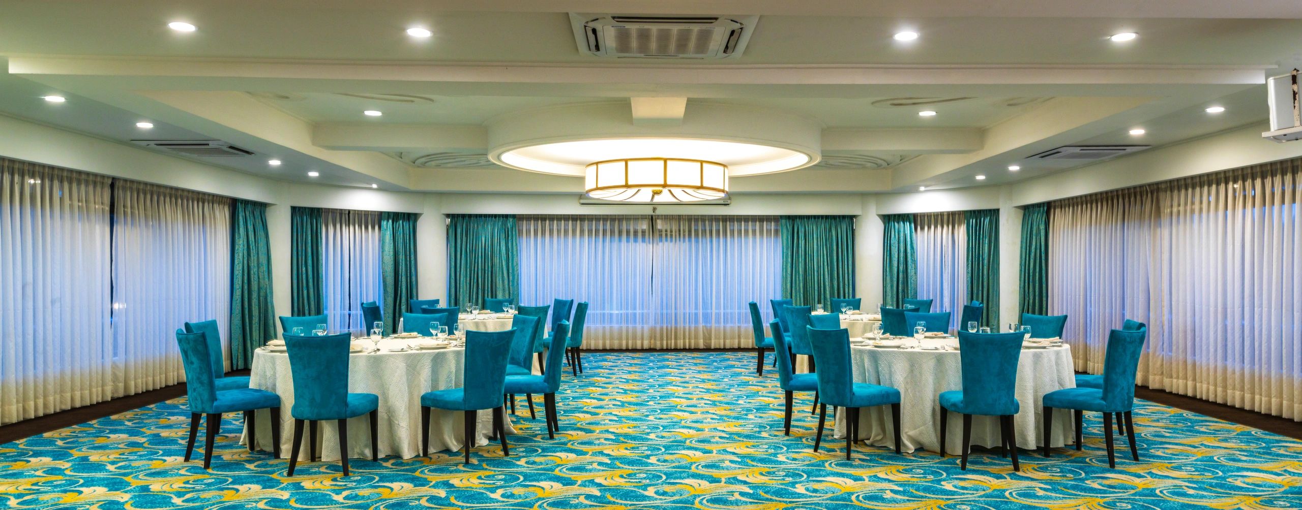 Elegant dining room with turquoise chairs and patterned carpet.