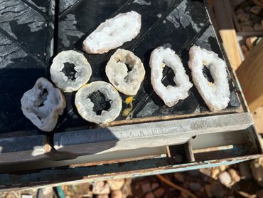 Various white geode slices laid out on a black surface with a ruler for scale.