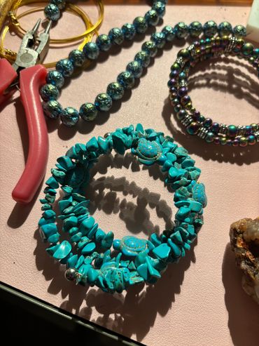 Turquoise turtle-themed beaded bracelet with jewelry tools on a table.