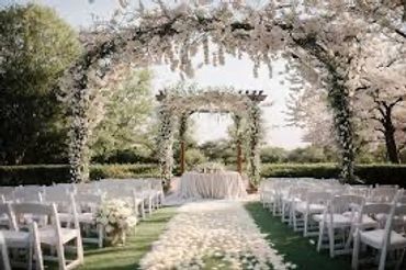 Elegant outdoor wedding setup with floral arches and white chairs.
