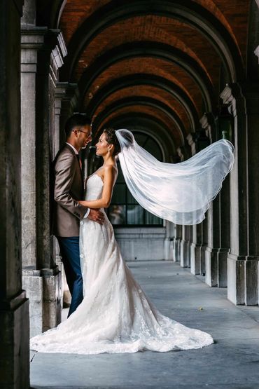 Bride and groom sharing a moment under arched brick architecture.