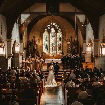 A wedding ceremony taking place in a grand church with stained glass windows.