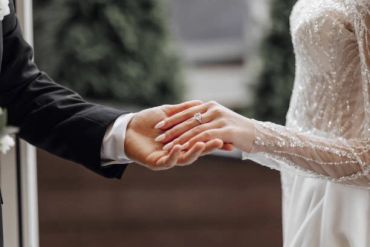 Bride and groom holding hands, showcasing the wedding ring.
