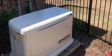 A Generac generator installed outside a brick house with an Eternal Power Electric service van in the background.